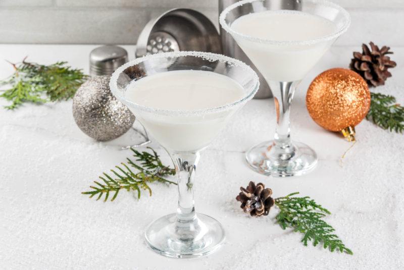 Two glasses of a white chocolate martini, next to tree sprigs and ornaments