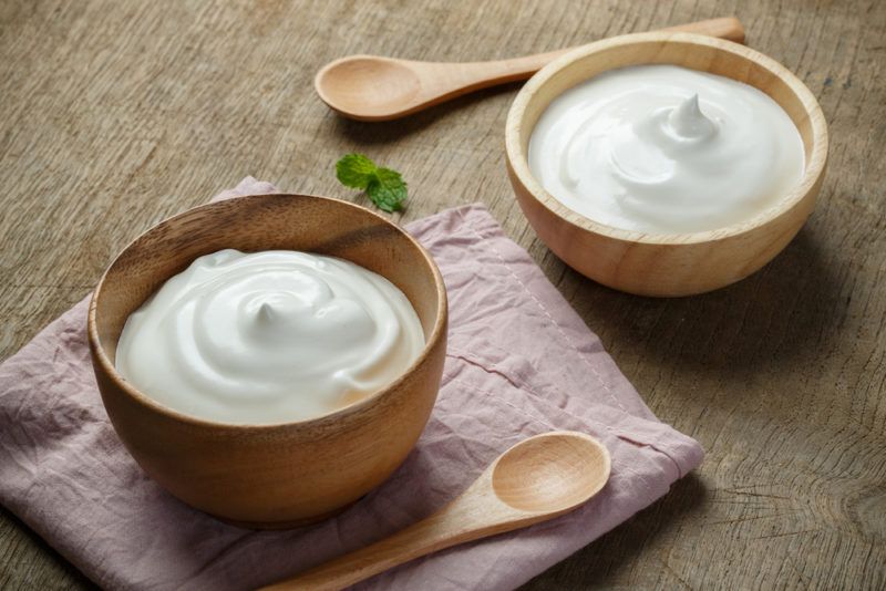 Two wooden bowls of mayonnaise that might go in a cocktail, next to two wooden spoons