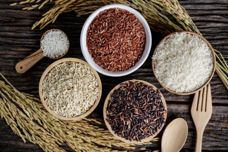 Little bowls of rice surrounded by stalks, next to wooden cutlery