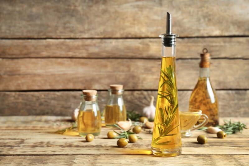 Glass bottles of olive oil on a wooden table against a wooden wall