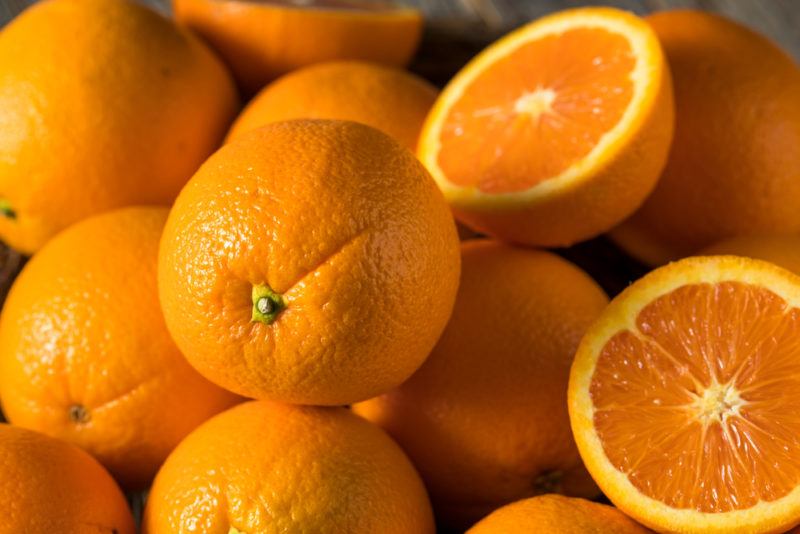 A selection of fresh navel oranges, where one has been sliced in half