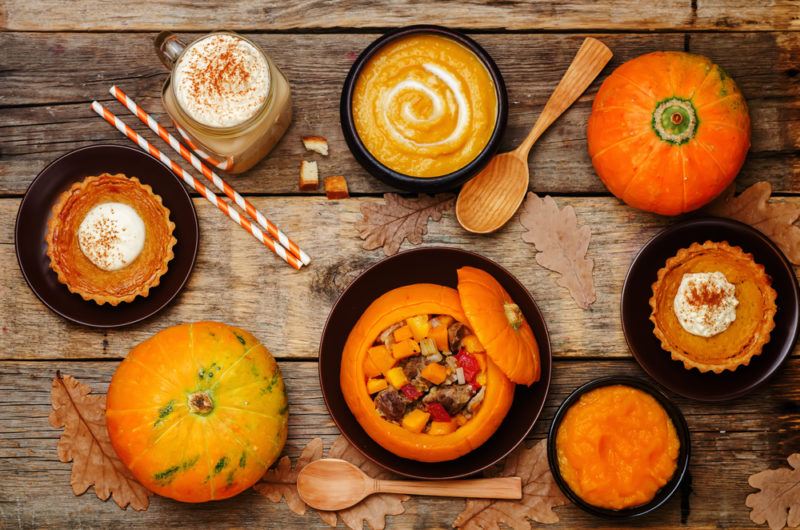 A selection of pumpkin dishes on a table, including pumpkin soup, pumpkin pie, and a pumpkin spice latte