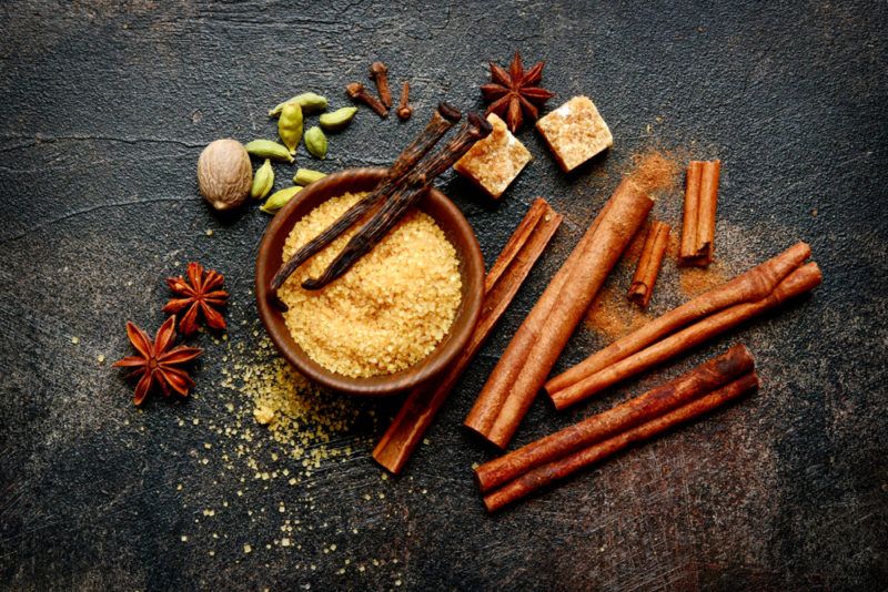 A collection of spices on a black background. The spices can all be used to make chai tea