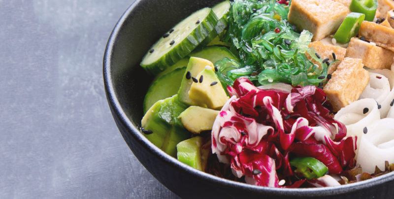 A black bowl with vegan ingredients and seaweed