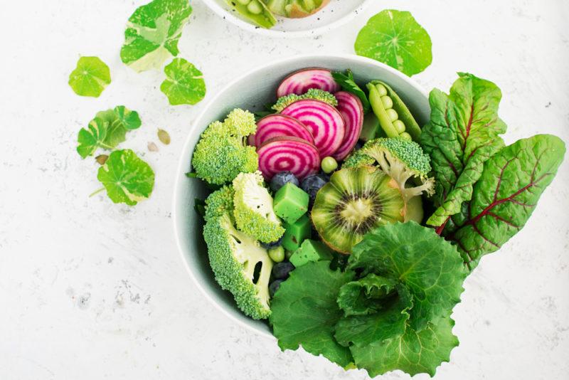 A bowl with greens and kiwis