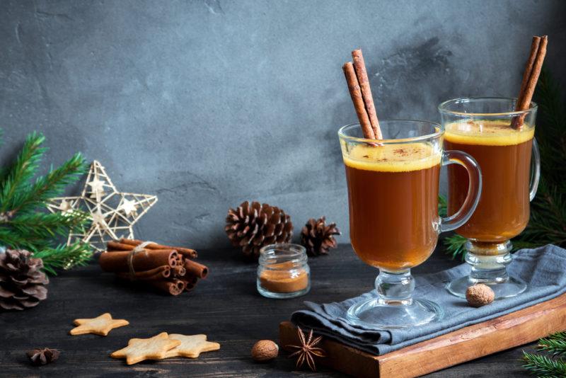 Two mugs of vegan hot buttered rum with cinnamon sticks