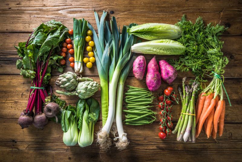 A flat lay of fresh vegetables, including carrots, beans, and bok choy