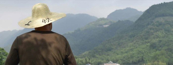 A man in a hat looking over beautiful hills