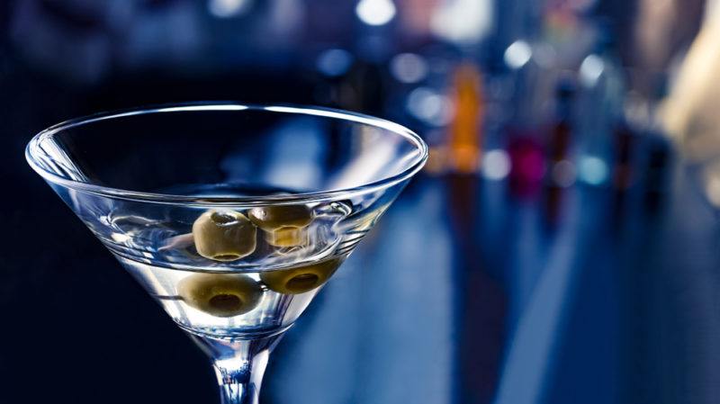 A martini with olives in front of a bar