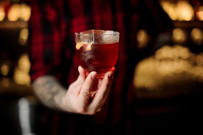 A bartender holding a Vieux Carre cocktail