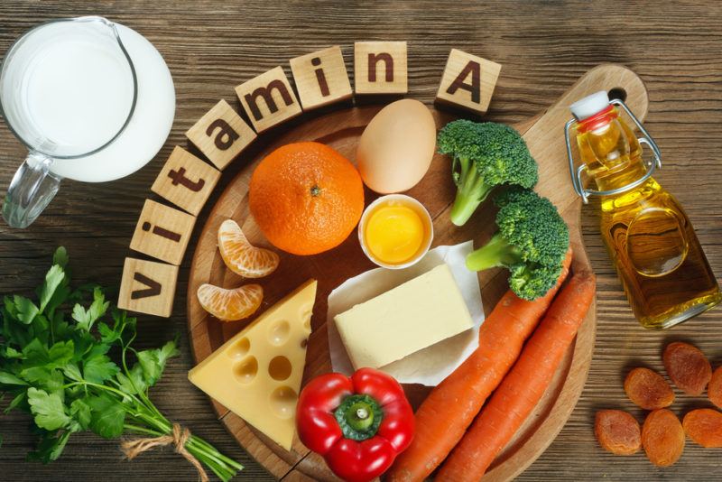 A wooden board with vitamin A rich foods, including cheese and vegetables