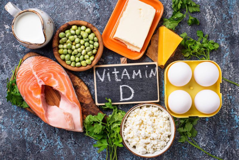 A black table with vitamin D rich foods including salmon and cheese