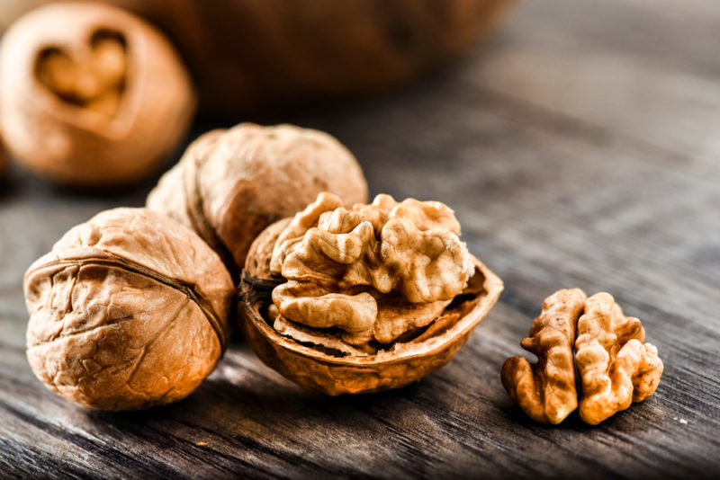 A couple of whole walnuts and a walnut out of its shell on a table