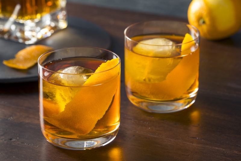 Two glasses containing an old fashioned cocktail and ice