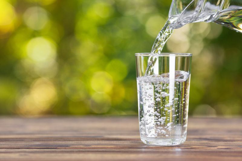 Water being poured into a glass on a table outside