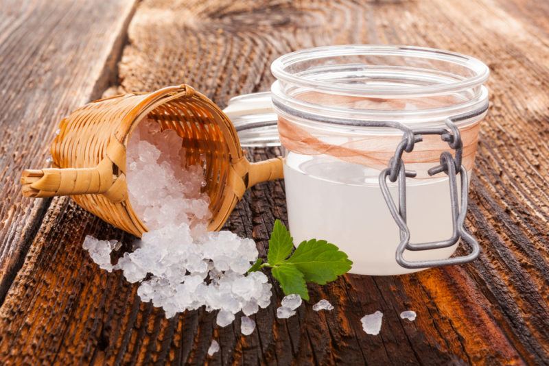 A glass jar containing water kefir and a scoop with the kefir grains