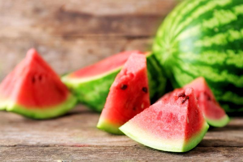 A watermelon on a table with watermelon chunks