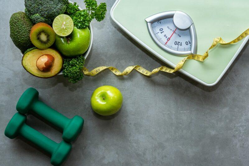 A scale, a tape measure, two hand weights and fresh fruits