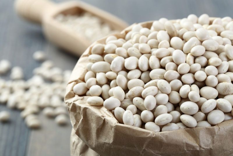 A bowl and a spoon containing white beans