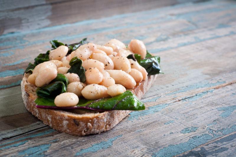 A piece of toast or bread with white beans and spinach