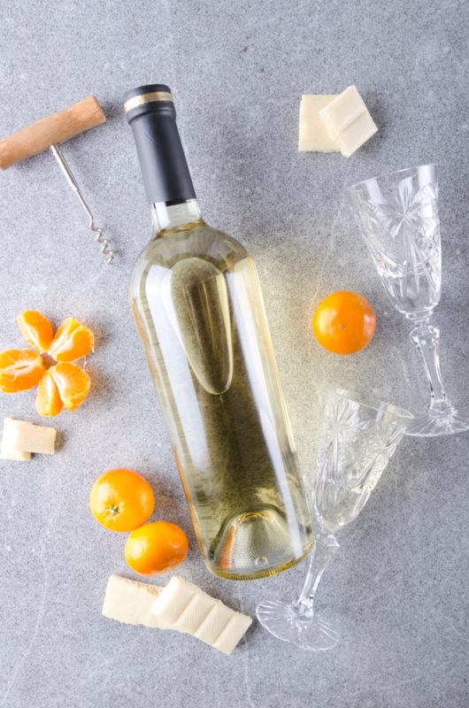 A bottle of off dry reisling, surrounded by white chocolate and mandarins