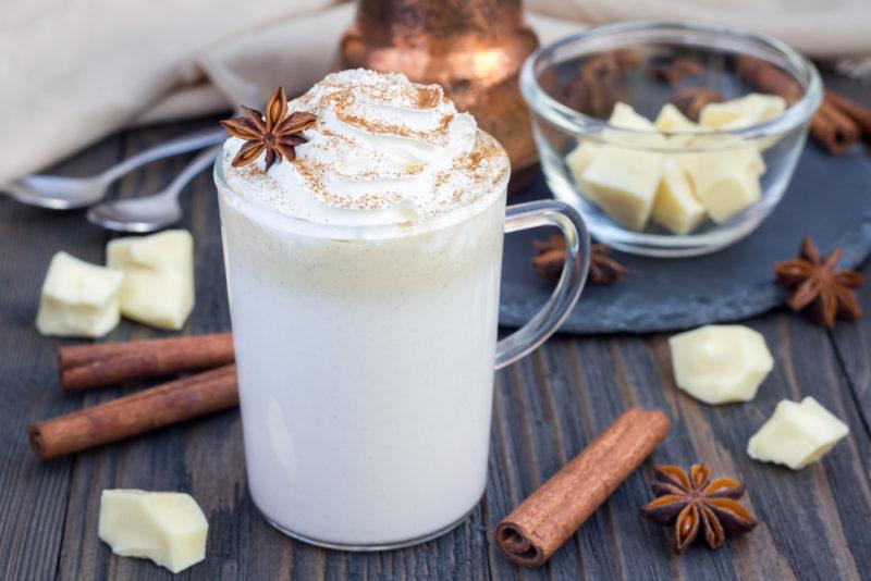 A white hot chocolate with various pieces of cocoa butter and cinnamon sticks