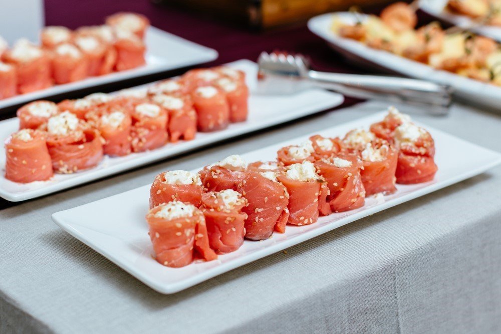 Three white plates with cream cheese that has been wrapped with salmon