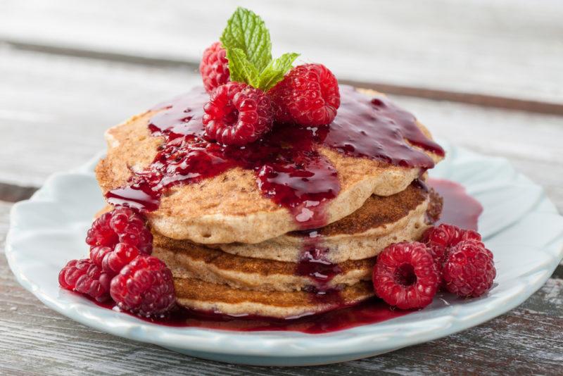 A stack of whole grain pancakes, with berries and sauce