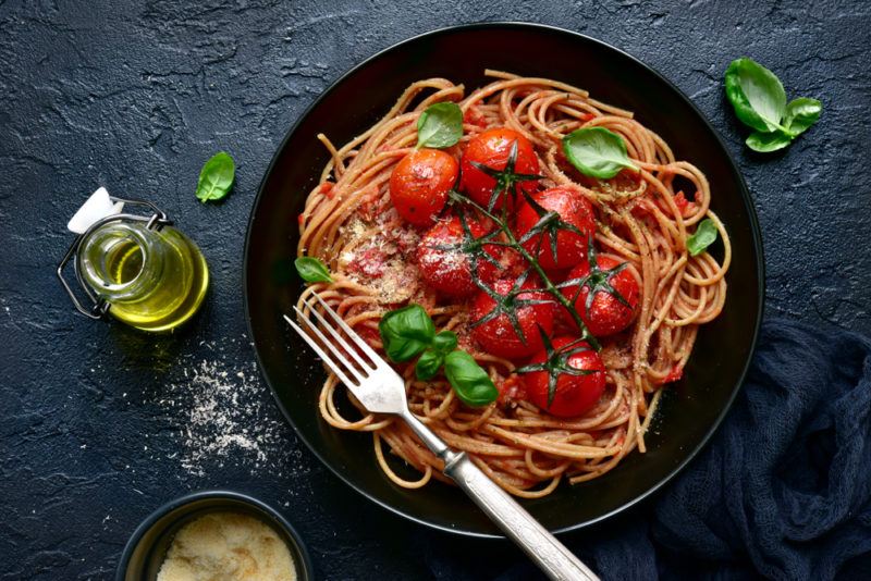 A black bowl with wholegrain pasta and tomatoes