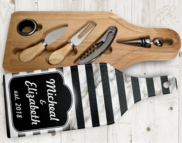 Wine-And-Cheese-Cutting-Board-Set | Food For Net A wooden tray containing various cheese and wine tools, next to a black and white glass lid.