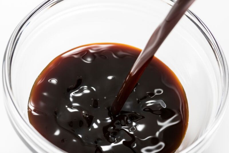 closeup image of a clear glass bowl with Worcestershire sauce being poured into it