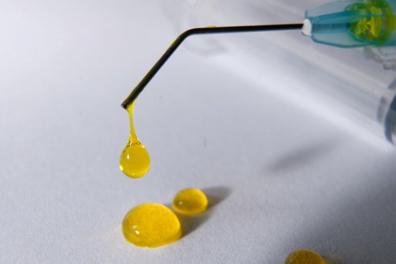 A dropper dispensing bright yellow riboflavin liquid