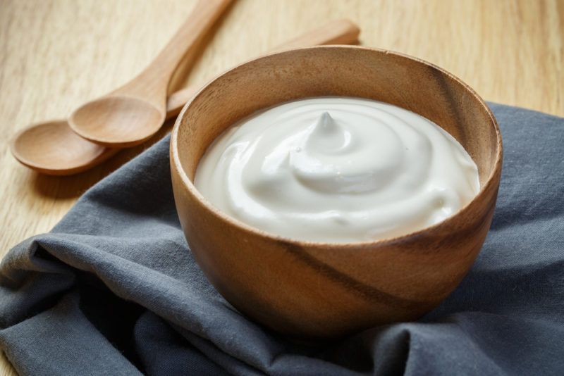 A wooden bowl of yogurt and two spoons