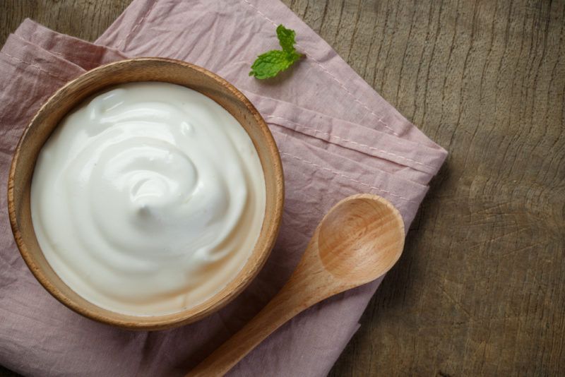 A wooden bowl of yogurt and a spoon