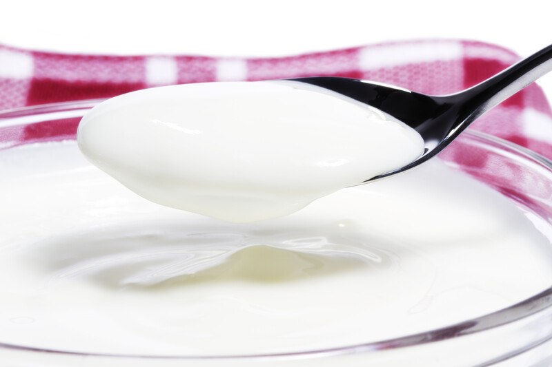 Yogurt For Chemo | Food For Net This photo shows white yogurt on a silver spoon hovering above a bowl of yogurt next to a red and white cloth.