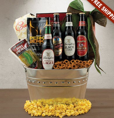 Silver bucket fulled with various bottles of beer and snacks. The bottom is surrounded with popcorn.