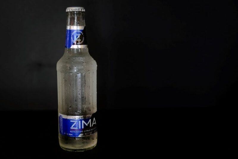 A bottle of clear alcohol called Zima isolated against a black background