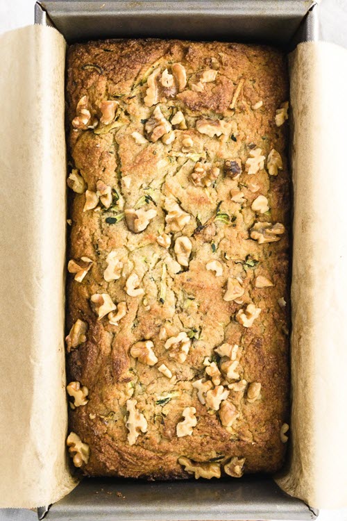 A bread pan containing zucchini bread with walnuts