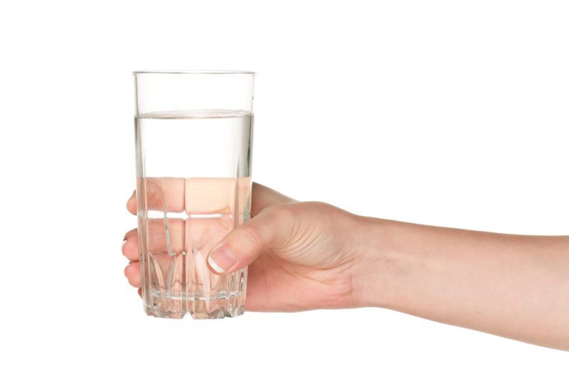 a glass of water in someone's hand, in a white background