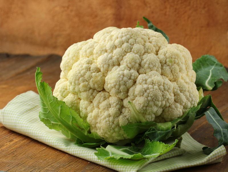 a whole head of cauliflower, a napkin, on a wooden table