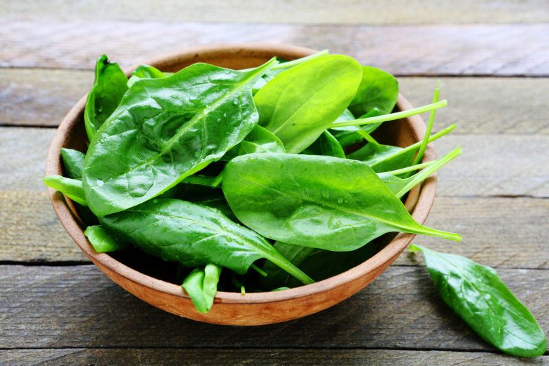 closeup shot  of a wooden bowl with spinach leaves