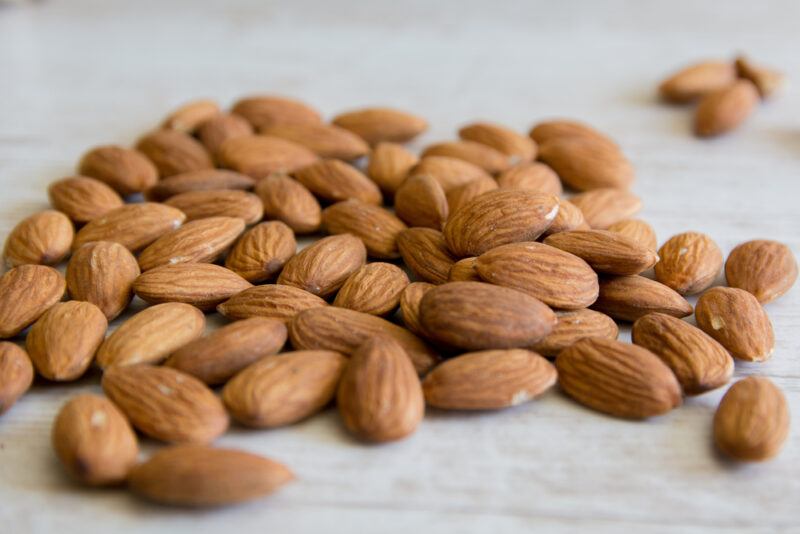 on a white wooden surface is a pile of almonds