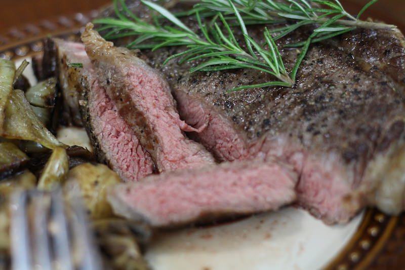 perfectly cooked sous vide steak with rosemary garnish and mushrooms