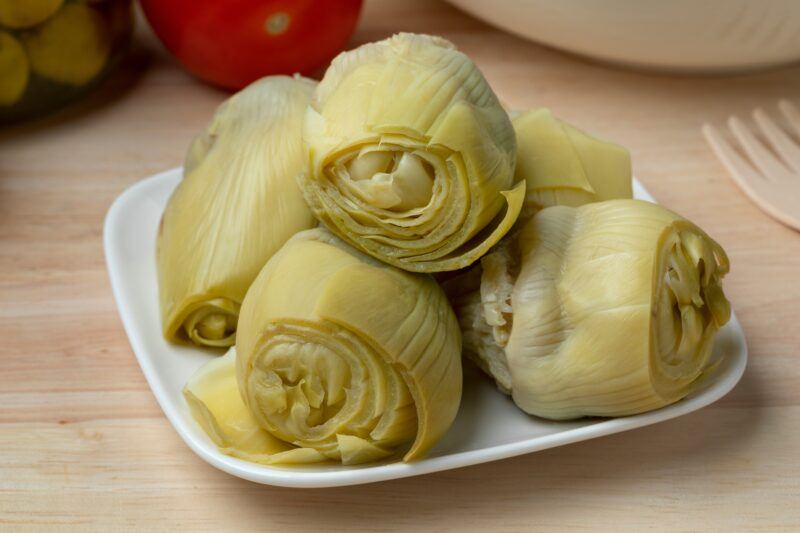 a white dish of with a pile of cooked heart artichokes