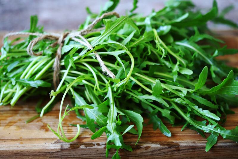 on a wooden board is a bunch of fresh arugula