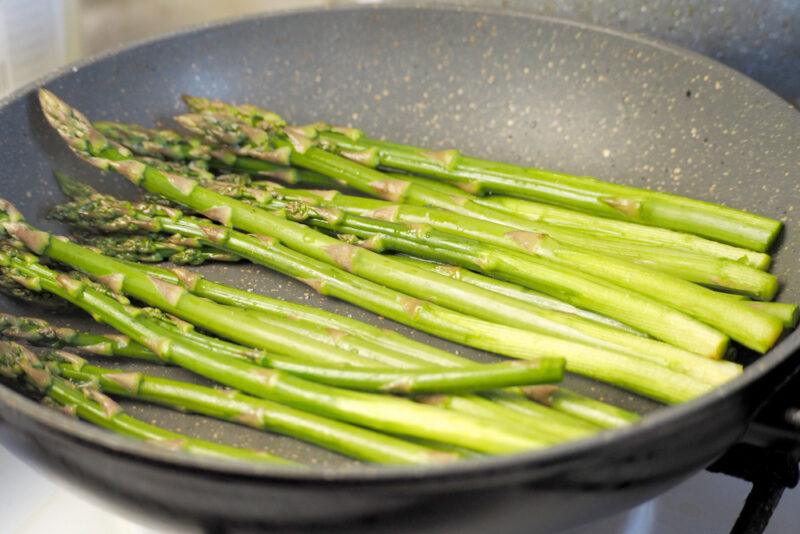 closeup image of a frying pan with asparagus