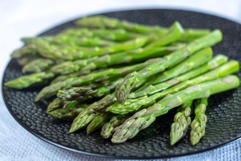 a closeup image of a black plate with fresh asparagus