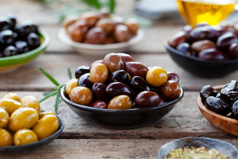 on a rustic wooden surface are different dishes with assorted fresh olives