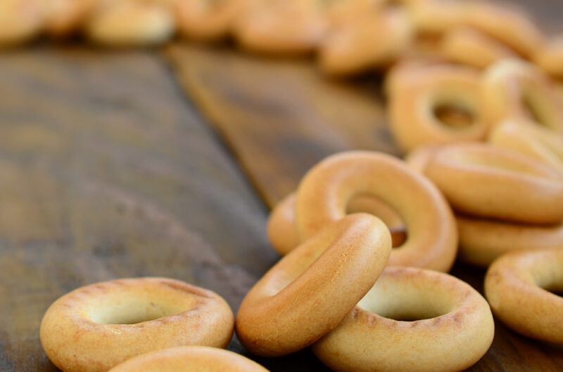 on a rustic looking wooden surface is a spread of plain bagels