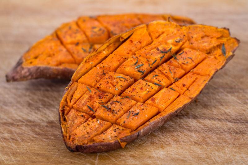 baked potato scored and dusted with spices and herbs, resting on a wooden surface